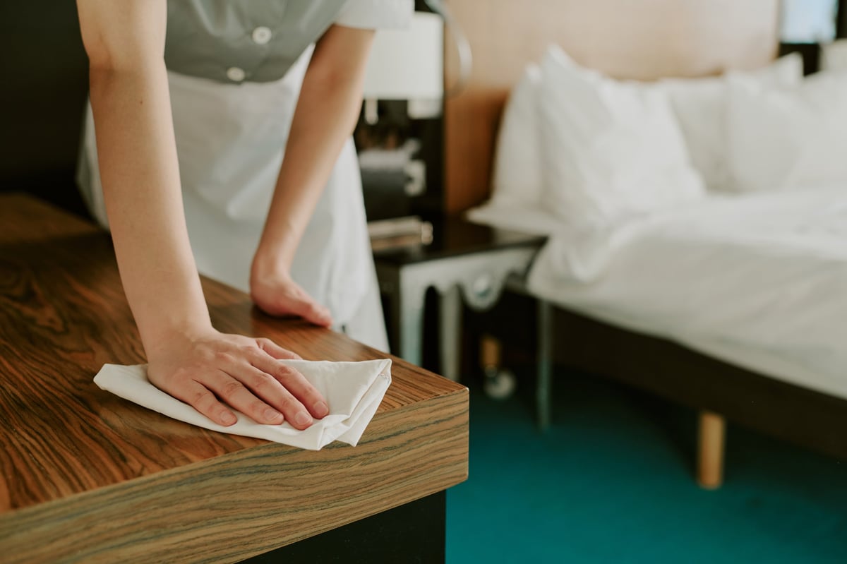 Cleaner dusting a wooden table with a soft cloth