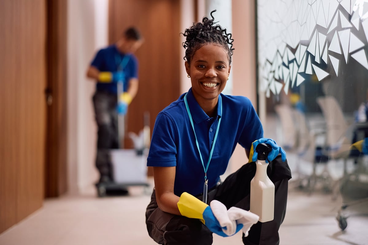Professional cleaner wiping glass walls in a bright office building